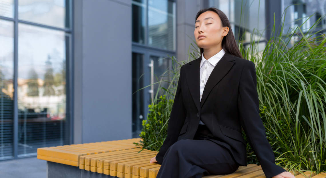 Asian businesswoman enjoys outdoor relaxation and meditation during work break.