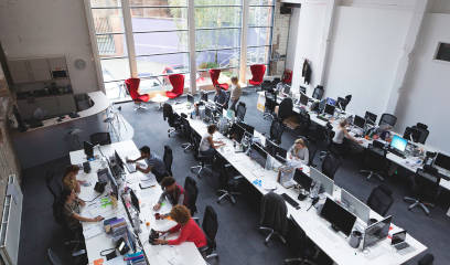 Professionals collaborating in spacious NYC office with versatile workstations.
