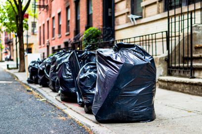 Garbage bags on Manhattan street, showcasing NYC waste's impact on commercial real estate.