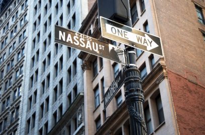 Street signs in Lower Manhattan, NYC, with Financial District office buildings in the background.