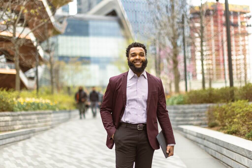A young African-American male political figure walking on the street in Hudson Yards.