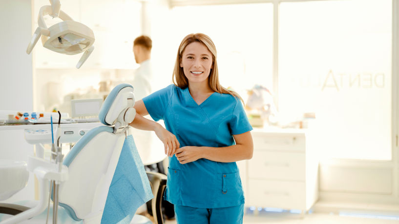 Female dentist in blue coat smiling at camera in a modern dental office